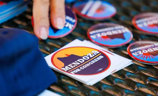 Volunteers take campaign pins and stickers supporting JoAnna Mendoza (D), an Arizona Congressional District 6 candidate, before a weekly neighborhood canvass, Thursday, Oct. 15, 2026, in Oro Valley, Ariz. (AP Photo/Mike Christy)