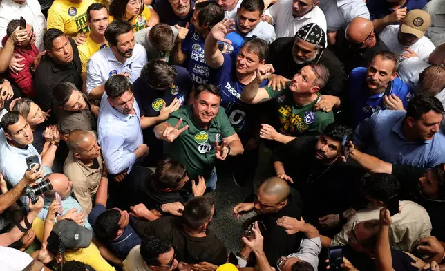 Opposition presidential candidate Sen. Flavio Bolsonaro, center, wearing a green shirt and looking up, campaigns in Sao Paulo, Brazil, Monday, Sept. 28, 2026. (AP Photo/Allison Sales)