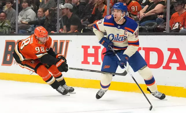 Edmonton Oilers center Connor McDavid, right, tries to pass while under pressure from Anaheim Ducks defenseman Pavel Mintyukov during the first period of an NHL hockey game Wednesday, Oct. 7, 2026, in Anaheim, Calif. (AP Photo/Mark J. Terrill)
