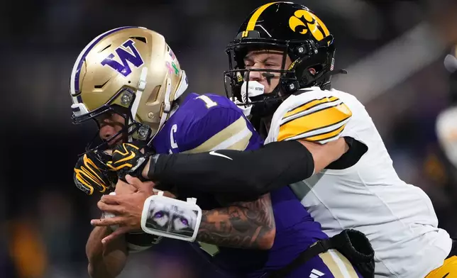 Iowa defensive back Zach Lutmer, right, tackled Washington quarterback Demond Williams Jr. during the first half of an NCAA college football game, Friday, Oct. 9, 2026, in Seattle. (AP Photo/Lindsey Wasson)