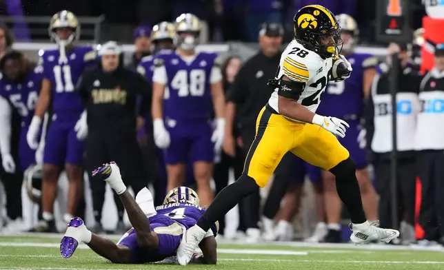 Iowa running back Kamari Moulton evades a tackle from Washington safety Rylon Dillard-Allen (4) to run for a touchdown during the first half of an NCAA college football game, Friday, Oct. 9, 2026, in Seattle. (AP Photo/Lindsey Wasson)