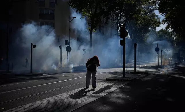 A student runs out the teargas during a protest against under-resourced schools in Lyon, France, Friday, Oct. 2, 2026. (AP Photo/Laurent Cipriani)