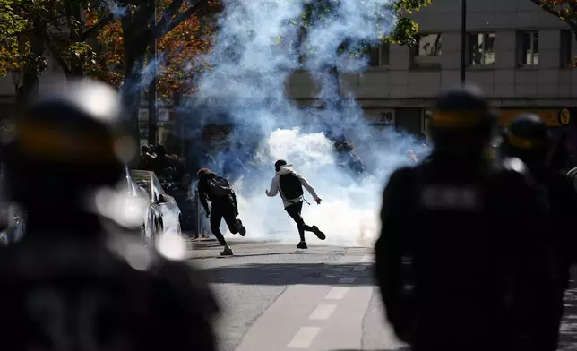 Students run through teargas as they face policemen during a protest against under-resourced schools, in Paris, Friday, Oct. 2, 2026. (AP Photo/Aurelien Morissard)