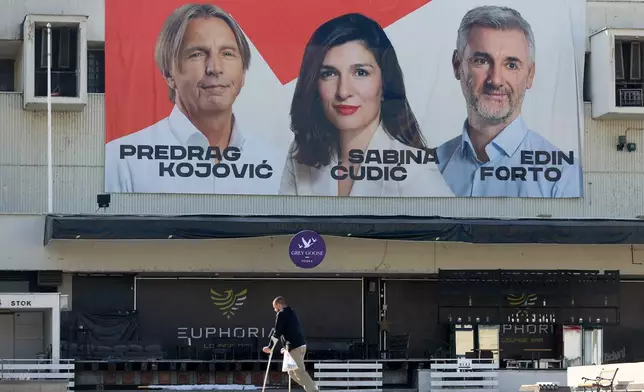 A man walks beneath an election poster featuring Our Party (NS) candidates for the upcoming general elections in Sarajevo, Bosnia, on Sept. 29, 2026. (AP Photo/Armin Durgut)