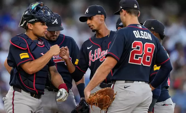 Atlanta Braves starting pitcher Ray Kerr, center, bumps fists with catcher Drake Baldwin as he exits during the third inning of Game 2 of a National League Division Series baseball game against the Los Angeles Dodgers Sunday, Oct. 4, 2026, in Los Angeles. (AP Photo/Mark J. Terrill)