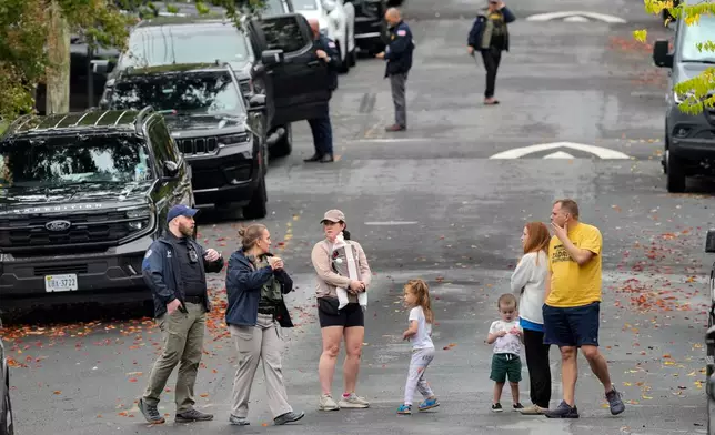 Homeland Security officers speak with local residents on 26th Street NE in Washington, early Monday, Oct. 12, 2026, during an investigation at the residence of Rep. Ilhan Omar, D-Minn. (AP Photo/J. Scott Applewhite)