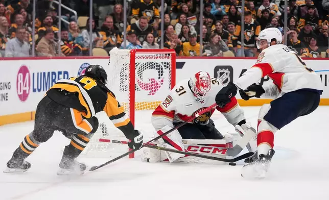 Florida Panthers goalie Cooper Black (31) blocks a shot by Pittsburgh Penguins' Connor Dewar (19) with Panthers' Aaron Ekblad, right, defending during the second period of an NHL hockey game in Pittsburgh, Thursday, Oct. 22, 2026. (AP Photo/Gene J. Puskar)