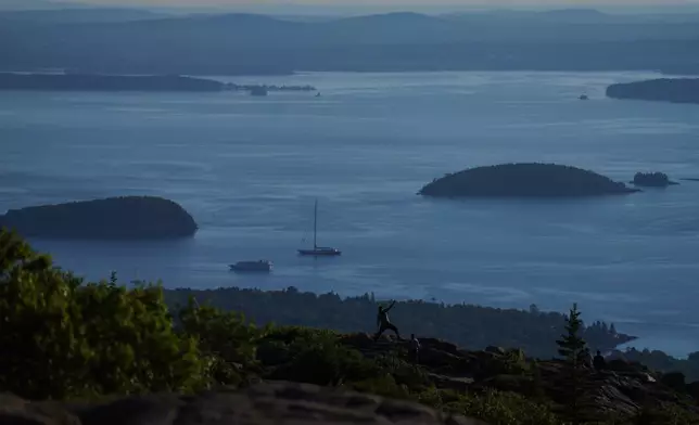 Visitors pose for photos at the summit of Cadillac Mountain in Acadia National Park in Maine, on Saturday, July 11, 2026. (AP Photo/Jessie Wardarski)