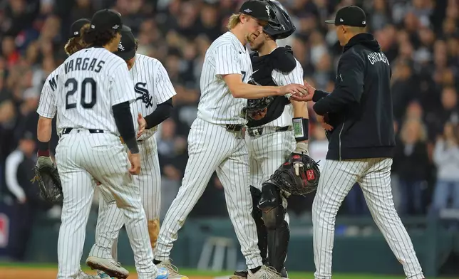 Chicago White Sox relief pitcher Erick Fedde, middle, hands the game ball to manager Will Venable, right, for a pitching change during the fifth inning of Game 4 of baseball's American League Division Series against the Cleveland Guardians, Thursday, Oct. 8, 2026, in Chicago. (AP Photo/Melissa Tamez)