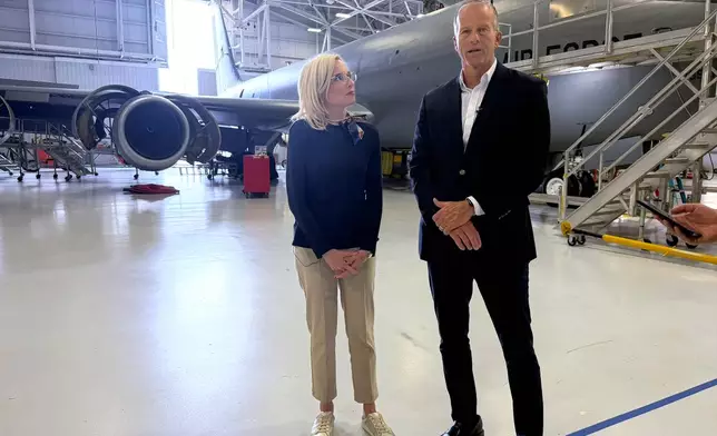 In this photo taken with a smart phone, Senate Majority Leader John Thune, R-S.D., right, and Iowa Rep. Ashley Hinson, a Republican running for Senate, talk to reporters at the 185th Air Refueling Wing, Iowa Air National Guard, Friday, Oct. 23, 2026, in Sioux City, Iowa. (AP Photo/AP Photo/Mary Clare Jalonick)