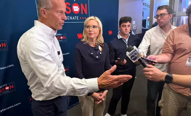 In this photo taken with a smart phone, Senate Majority Leader John Thune, R-SD., from left, and Iowa Rep. Ashley Hinson, a Republican running for Senate, talk to reporters at a campaign event, Friday, Oct. 23, 2026, in Sioux City, Iowa. (AP Photo/AP Photo/Mary Clare Jalonick)