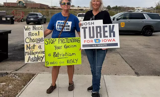 In this photo taken with a smart phone, Iowans Valerie Conaway Cote, a Democrat, right, and Jeanne Gates, an Independent, stage a small protest outside an event for Republican Senate candidate Ashley Hinson, Friday, Oct. 23, 2026, in Sioux City, Iowa. (AP Photo/AP Photo/Mary Clare Jalonick)