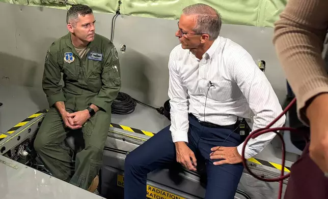 In this photo taken with a smart phone, Senate Majority Leader John Thune, R-SD., seated right, is briefed during a tour of a KC-135 Stratotanker at the 185th Air Refueling Wing, Iowa Air National Guard, Friday, Oct. 23, 2026, in Sioux City, Iowa. (AP Photo/AP Photo/Mary Clare Jalonick)
