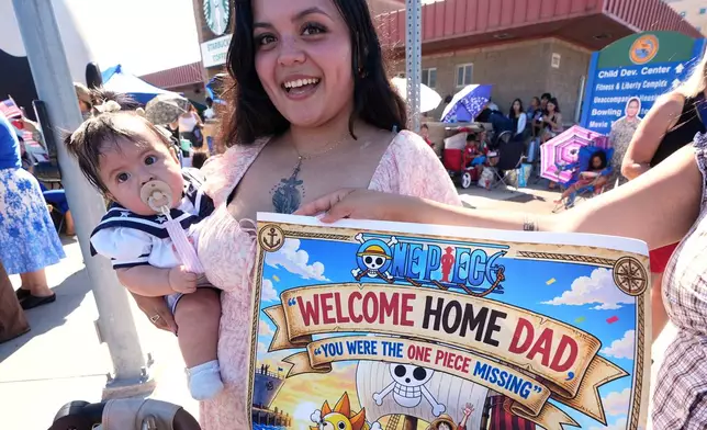 Kathy Monterroso, center, holding her daughter Sarahi Monterroso, waits to greet her husband, sailor Chris Monterroso as the USS Abraham Lincoln aircraft carrier returns to Naval Air Station North Island after deployment Thursday, Oct. 8, 2026, in Coronado, Calif. (AP Photo/Gregory Bull)