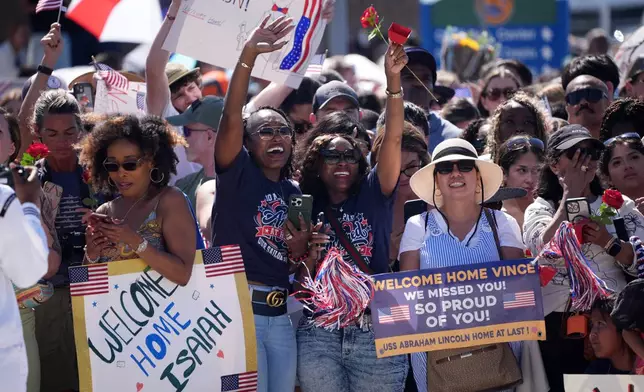 Family and friends cheer as the USS Abraham Lincoln aircraft carrier returns to Naval Air Station North Island after deployment Thursday, Oct. 8, 2026, in Coronado, Calif. (AP Photo/Gregory Bull)
