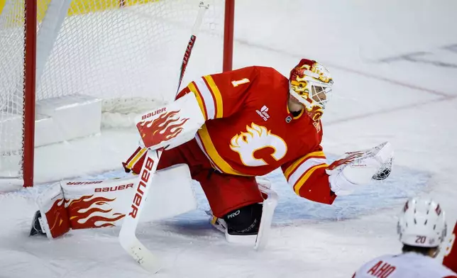 Carolina Hurricanes' Sebastian Aho (20) looks on as Calgary Flames goalie Devin Cooley (1) grabs his shot during the second period of an NHL hockey game in Calgary, Alberta, Sunday, Oct. 18, 2026. (Jeff McIntosh/The Canadian Press via AP)