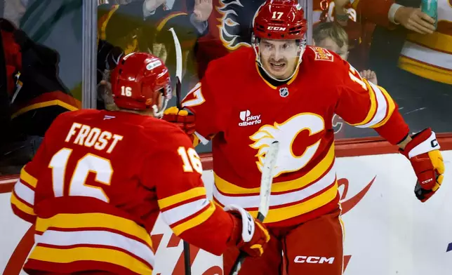 Calgary Flames' Yegor Sharangovich, right, celebrates his goal with teammate Morgan Frost during the third period of an NHL hockey game against the Carolina Hurricanes in Calgary, Alberta, Sunday, Oct. 18, 2026. (Jeff McIntosh/The Canadian Press via AP)