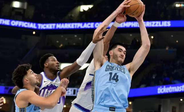 Memphis Grizzlies center Zach Edey (14) grabs a rebound ahead of, from left, guard Jahmai Mashack, Utah Jazz forward Jaren Jackson Jr., and center Jaxson Hayes in the first half of an NBA basketball game Wednesday, Oct. 21, 2026, in Memphis, Tenn. (AP Photo/Brandon Dill)