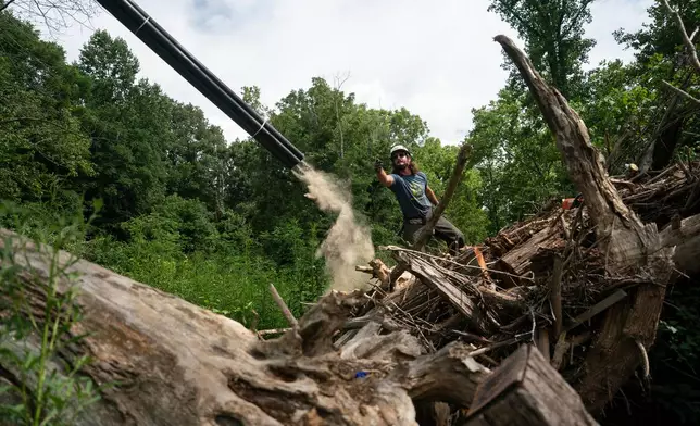 Workers from MountainTrue clear IPEX PVC pipe from the riverbank Wednesday, July 22, 2026, in Alexander, N.C. (AP Photo/Allison Joyce)
