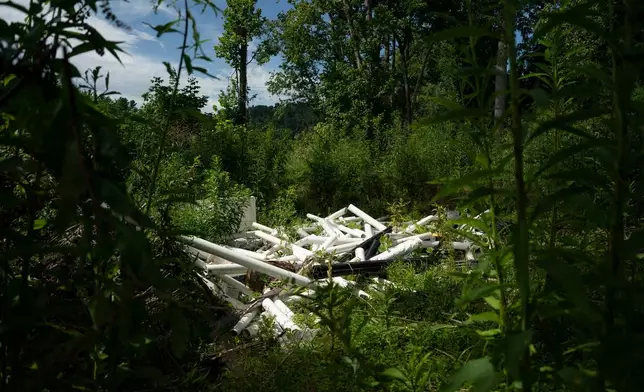 Workers from MountainTrue clear IPEX PVC pipe from the riverbank Wednesday, July 22, 2026, in Alexander, N.C. (AP Photo/Allison Joyce)