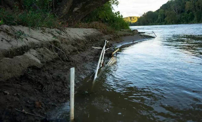 PVC pipe is stuck in the mud and in the French Broad River directly on the riverbank in front of the IPEX factory that makes the pipes Thursday, Sept. 24, 2026, in Woodfin, N.C. (AP Photo/Allison Joyce)