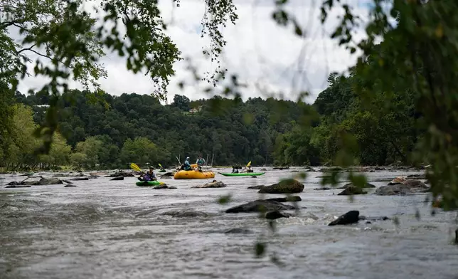 Workers from MountainTrue paddle IPEX PVC pipe they collected from the riverbank Wednesday, July 22, 2026, in Alexander, N.C. (AP Photo/Allison Joyce)