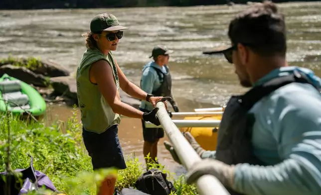 Workers from MountainTrue clear IPEX PVC pipe from the riverbank Wednesday, July 22, 2026, in Alexander, N.C. (AP Photo/Allison Joyce)