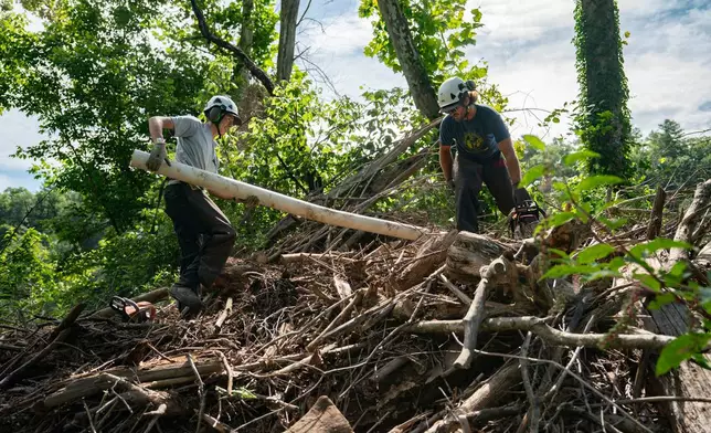 Workers from MountainTrue clear IPEX PVC pipe from the riverbank Wednesday, July 22, 2026, in Alexander, N.C. (AP Photo/Allison Joyce)