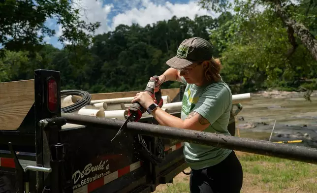 A worker from MountainTrue cuts IPEX PVC pipe taken from the riverbank so that it can fit in the truck Wednesday, July 22, 2026, in Alexander, N.C. (AP Photo/Allison Joyce)