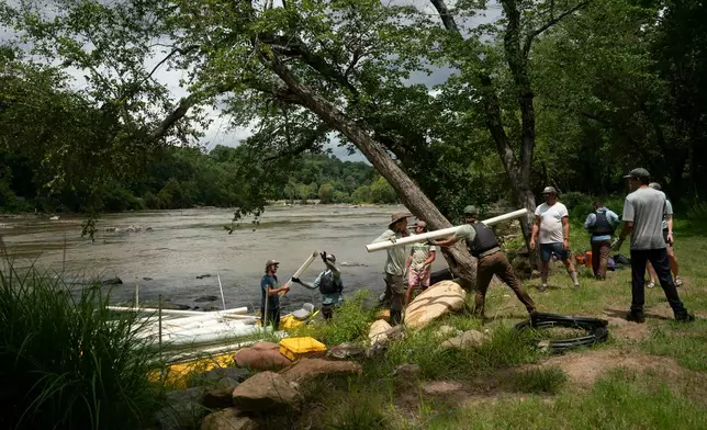 Workers from MountainTrue clear IPEX PVC pipe from the riverbank Wednesday, July 22, 2026, in Alexander, N.C. (AP Photo/Allison Joyce)