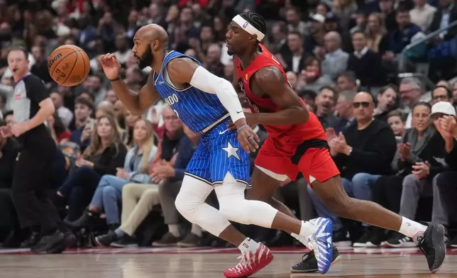Orlando Magic's Jevon Carter, left, battles for the ball against Toronto Raptors' Ja'kobe Walter (14) during the first half of an NBA basketball game in Toronto, Wednesday, Oct. 28, 2026. (Nathan Denette/The Canadian Press via AP)