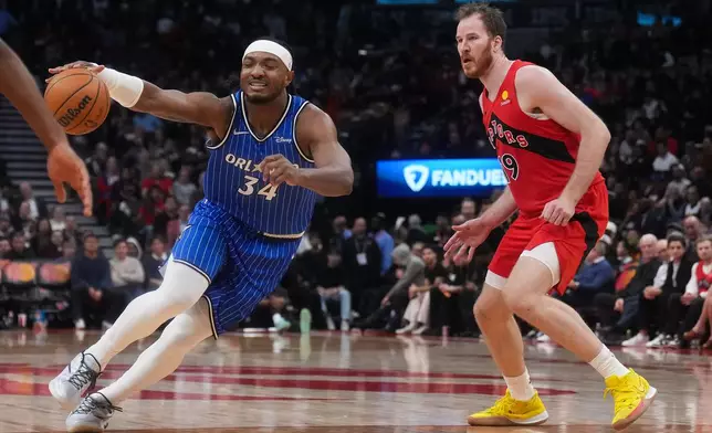 Orlando Magic's Wendell Carter Jr. (34) tries too drive past Toronto Raptors' Jakob Poeltl (19) during second half of an NBA basketball game in Toronto, Wednesday, Oct. 28, 2026. (Nathan Denette/The Canadian Press via AP)