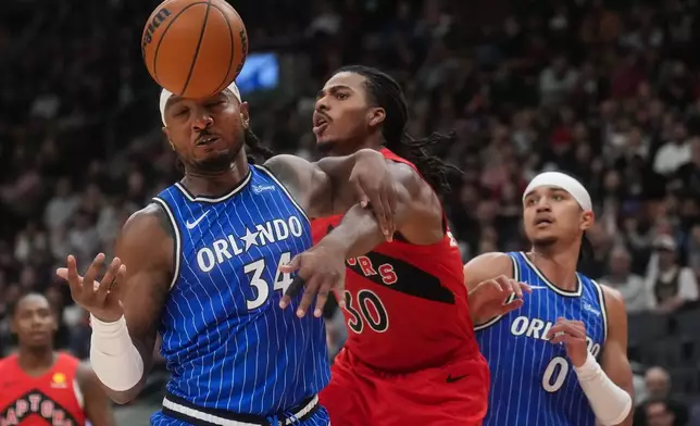 Orlando Magic's Wendell Carter Jr. (34) and Toronto Raptors' Collin Murray-Boyles (30) battle for a loose ball during the first half of an NBA basketball game in Toronto, Wednesday, Oct. 28, 2026. (Nathan Denette/The Canadian Press via AP)