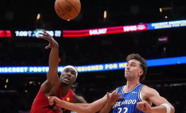 Toronto Raptors' Ja'kobe Walter (14) battles for the ball against Orlando Magic's Franz Wagner (22) during the second half of an NBA basketball game in Toronto, Wednesday, Oct. 28, 2026. (Nathan Denette/The Canadian Press via AP)