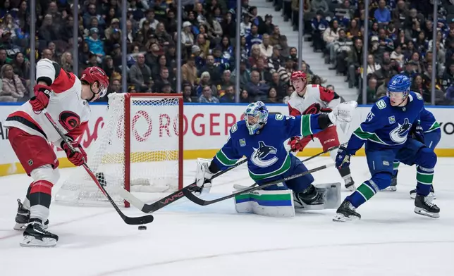 Vancouver Canucks goaltender Leevi Merilainen (31) stops Carolina Hurricanes' Andrei Svechnikov (37) as Vancouver's Elias Pettersson (25) watches during the second period of an NHL hockey game in Vancouver on Tuesday, Oct. 20, 2026. (Ethan Cairns/The Canadian Press via AP)