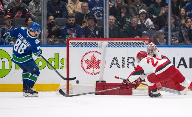 Vancouver Canucks' Jonathan Lekkerimaki (88) scores on Carolina Hurricanes goaltender Pyotr Kochetkov (52) as Sebastian Aho (20) defends during the first period of an NHL hockey game in Vancouver on Tuesday, Oct. 20, 2026. (Ethan Cairns/The Canadian Press via AP)