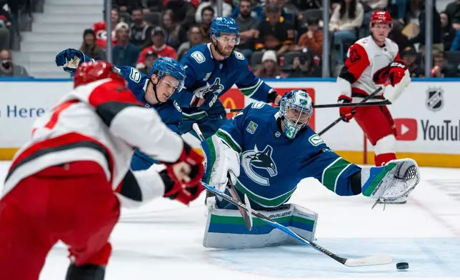 Carolina Hurricanes' Nikolaj Ehlers (front left) scores on Vancouver Canucks goaltender Leevi Merilainen (31) as Tom Willander (5) defends during the first period of an NHL hockey game in Vancouver on Tuesday, Oct. 20, 2026. (Ethan Cairns/The Canadian Press via AP)