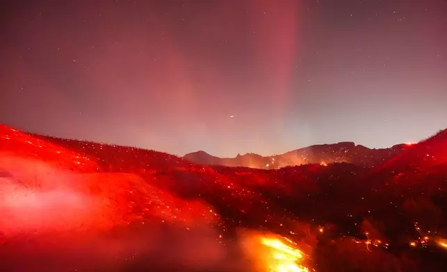 Hot spots glow across a hillside during the Bryson Fire in Malibu, Calif., Thursday, Oct. 15, 2026. (AP Photo/Jae C. Hong)