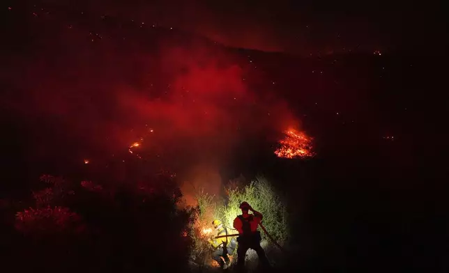 Crews make a stand in front of the Bryson Fire on Thursday, Oct. 15, 2026, in Malibu, Calif. (AP Photo/Jae C. Hong)