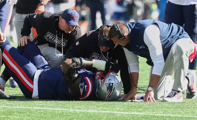 New England Patriots head coach Mike Vrabel, right, checks on offensive tackle Morgan Moses as he lies on the field during the first half of an NFL football game New York Jets in Foxborough, Mass., Sunday, Oct. 18, 2026. (AP Photo/Mark Stockwell)