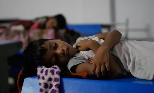 A child rests on a bench at a temporary shelter set up inside a school as Cyclone Arnab approaches the Andhra Pradesh coast in Kakinada, India, late Tuesday, Oct. 27, 2026. (AP Photo/Mahesh Kumar A.)