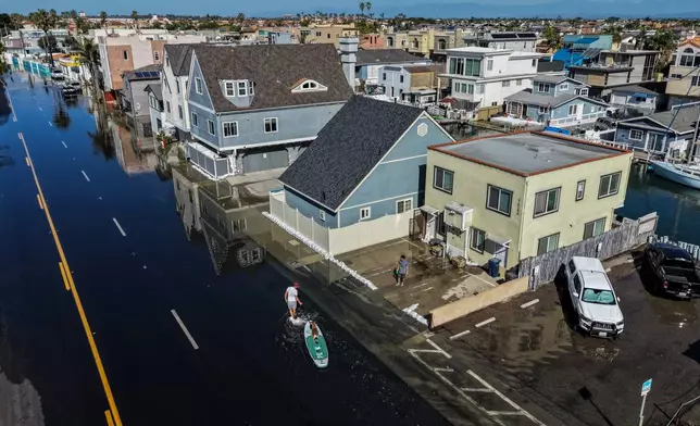 James Hays pulls his paddleboard through floodwaters on the Pacific Coast Highway in Huntington Beach, Calif., Wednesday, Oct. 28, 2026. (AP Photo/Jae C. Hong)