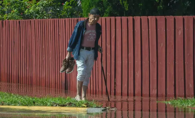 A pedestrian walk through a flooded street caused by king tides and heavy rain Wednesday, Oct. 28, 2026, in North Bay Village, Fla. (AP Photo/Marta Lavandier)