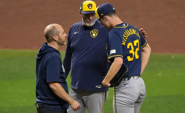 Milwaukee Brewers pitcher Jacob Misiorowski talks with head athletic trainer Brad Epstein and manager Kevin Cash after being pulled from the game during the sixth inning of Game 5 of baseball's World Series, Wednesday, Oct. 28, 2026, in St. Petersburg, Fla., between the Milwaukee Brewers and the Tampa Bay Rays. (AP Photo/Phelan M. Ebenhack)