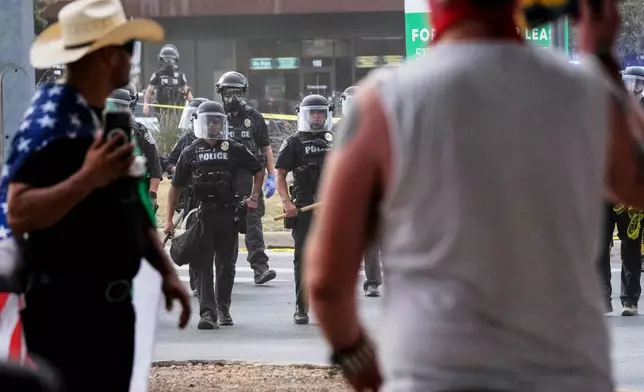 FILE - Authorities with batons stand near a demonstration where a man was shot in his vehicle by an ICE officer, Sept. 20, 2026, in Austin, Texas. (AP Photo/Joel Angel Juarez, File)