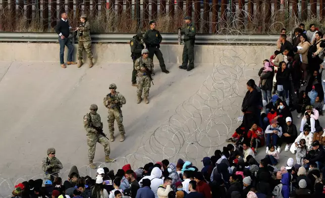 FILE - Migrants congregate on the banks of the Rio Grande at the U.S. border with Mexico on Dec. 20, 2022, where members of the Texas National Guard cordoned off a gap in the U.S. border wall. (AP Photo/Morgan Lee, File)