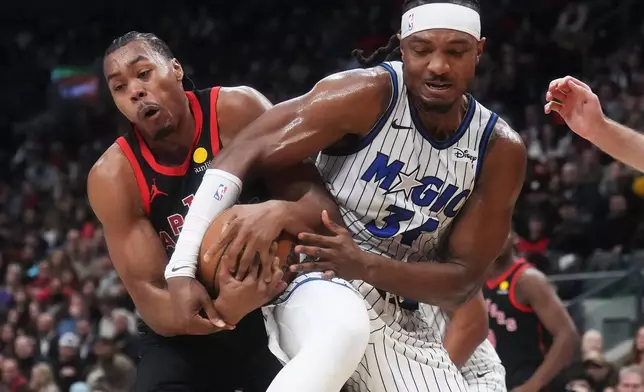 Toronto Raptors' Scottie Barnes (left) and Orlando Magic's Wendell Carter Jr. (34) battle for the ball during the first half of an NBA Cup basketball game in Toronto, Friday, Oct. 30, 2026. (Nathan Denette/The Canadian Press via AP)