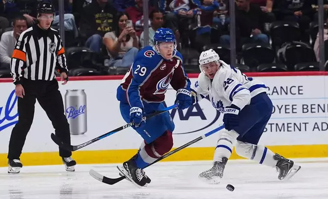 Toronto Maple Leafs defenseman Troy Stecher, right, is called for a penalty as he trips Colorado Avalanche center Nathan MacKinnon (29) in the second period of an NHL hockey game Saturday, Oct. 10, 2026, in Denver. (AP Photo/David Zalubowski)
