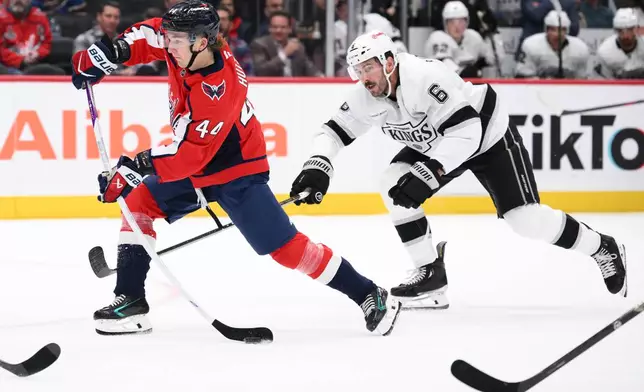 Washington Capitals defenseman Cole Hutson (44) shoots the puck against Los Angeles Kings defenseman Joel Edmundson (6) during the first period of an NHL hockey game, Tuesday, Oct. 20, 2026, in Washington. (AP Photo/Nick Wass)