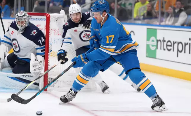 St. Louis Blues' Cam Fowler, right, controls the puck as Winnipeg Jets goaltender Stuart Skinner (74) and Adam Lowry defend during the second period of an NHL hockey game Tuesday, Oct. 20, 2026, in St. Louis. (AP Photo/Jeff Roberson)